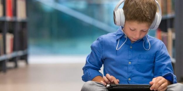 young male student listening to device to help learn, assistive technology