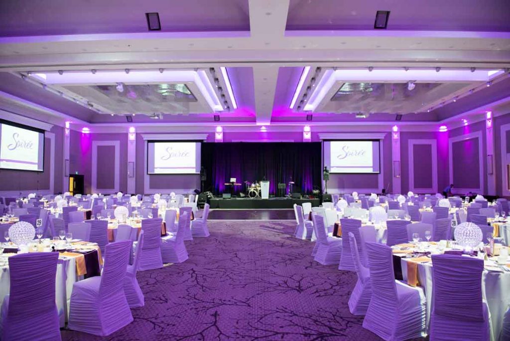 elegantly decorated tables in a purple-lit hall
