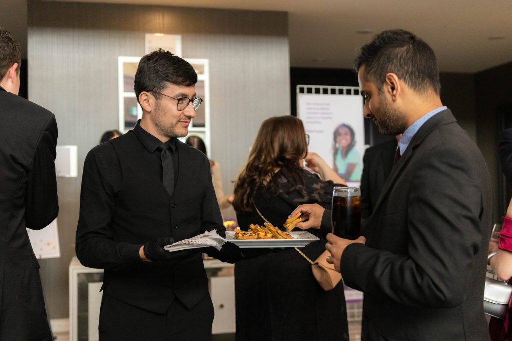 Man serving appetizers on a tray to another man